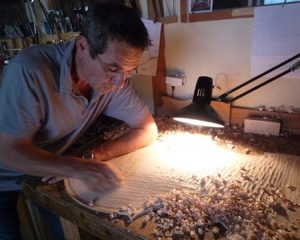 Luthier travaillant le bois à la lueur d'une lampe de chevet à bras flexible